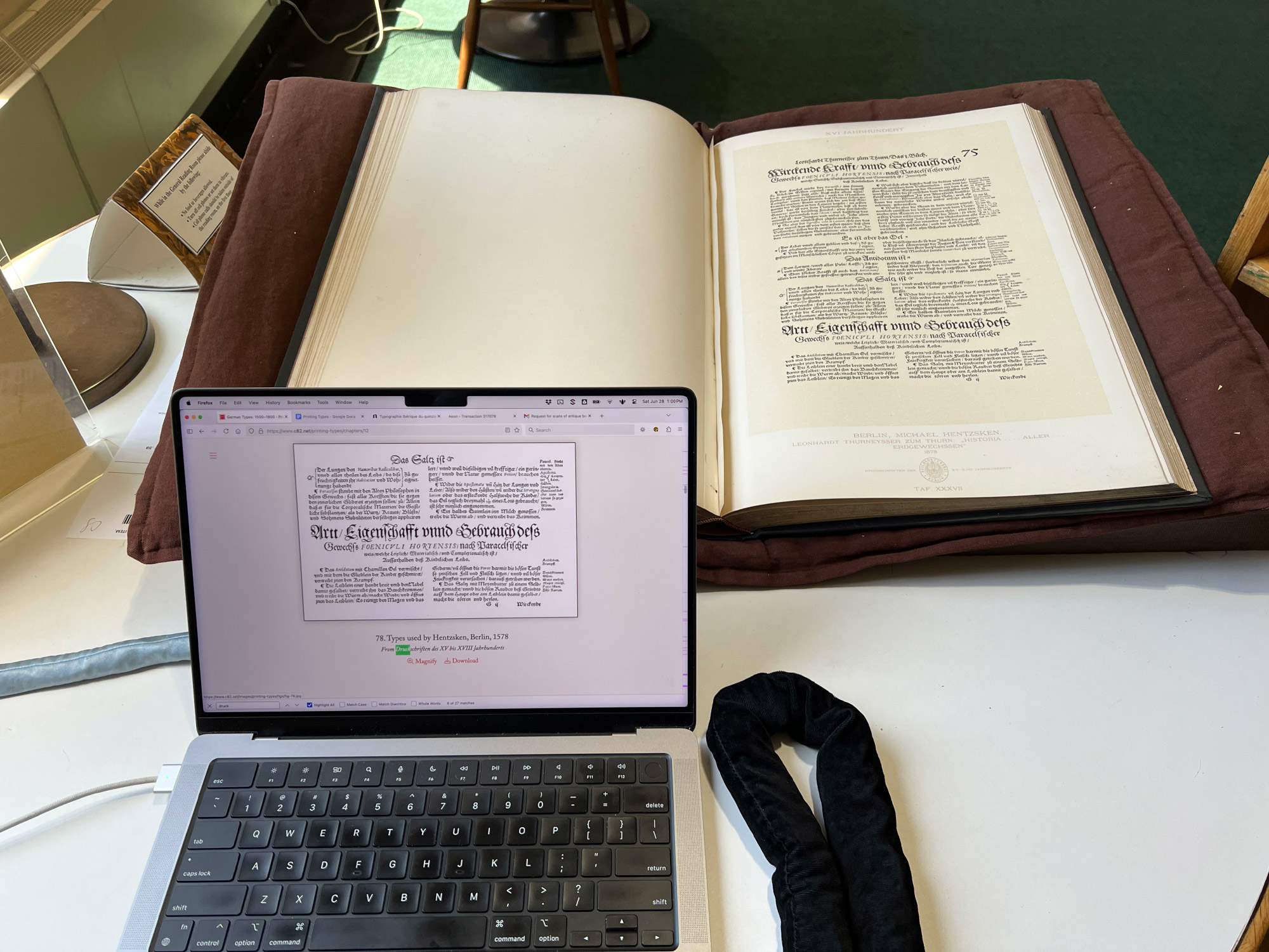 Photo of a large antique book from the late nineteenth century and matching facsimile from it on a laptop, taken at the Newberry Library in Chicago